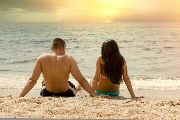 Deux jeunes profitent du coucher de soleil sur la plage, profitant de leurs vacances - Photo, image