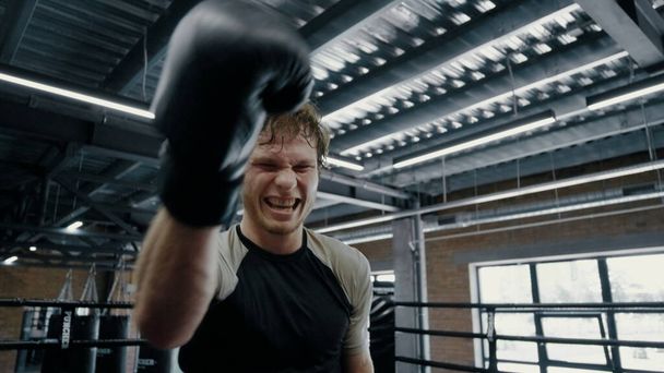 Deportista cándido mostrando agresión en el ring. Kickboxer progresa en el gimnasio - Foto, Imagen