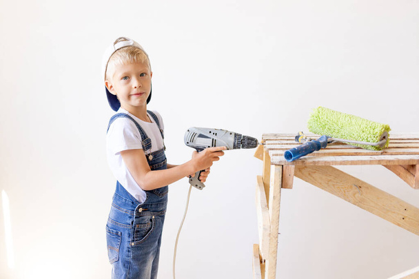 Niño en un casco juega en el constructor con herramientas. aislado sobre blanco. - Foto, imagen