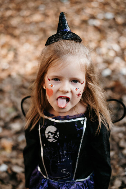 Αξιολάτρευτο κοριτσάκι φορώντας κοστούμι μάγισσα με σκούπα στο Halloween σε εξωτερικούς χώρους - Φωτογραφία, εικόνα