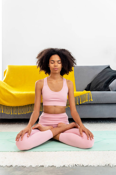 Afroamerican woman practicing yoga lotus pose to meditation at cozy home - Zdjęcie, obraz