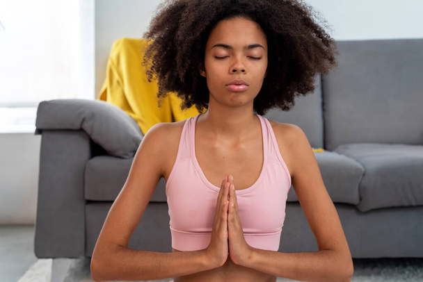 Афроамериканка практикующая йогу лотос позирует медитации в уютном доме - Фото, изображение