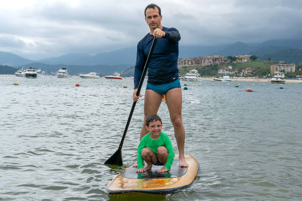 Padre e hijo en un stand up-paddle board (vista frontal). - Foto, Imagen