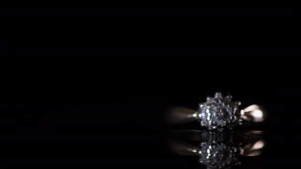Arany gyémánt eljegyzési gyűrű világít egy fekete tükröződő háttér - Felvétel, videó