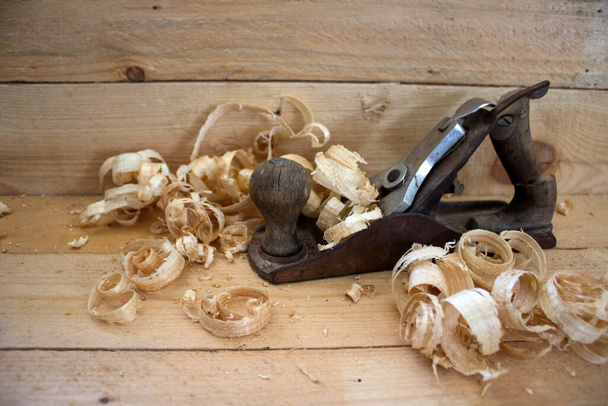 Wooden shavings and plane tool close up photo. Carpenter tools.  - Photo, Image