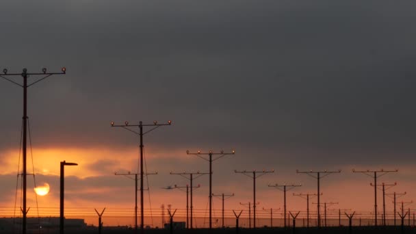 Letadlo přistávající na letišti LAX při západu slunce, Los Angeles, Kalifornie USA. Silueta letadla pro cestující nebo nákladní letadlo, dramatická oblačnost. Letadlo přilétá na letiště. Mezinárodní přeprava létání - Záběry, video