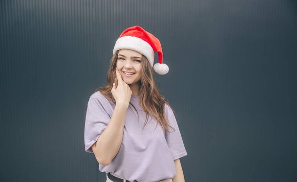 Young stylish trendy woman isolated over grey blue background. Positive stylish girl in red hat celebrating christmas or new year period. Festive holidays time. - Фото, зображення