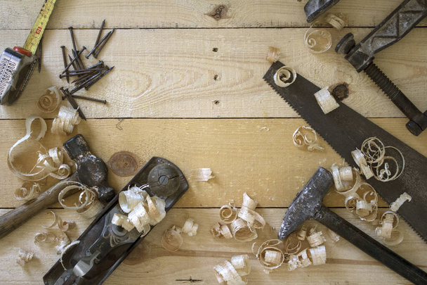 Carpenter tools close up photo.  Vintage hand saw, clamp, plane tool and wooden shavings top view.  - Photo, Image