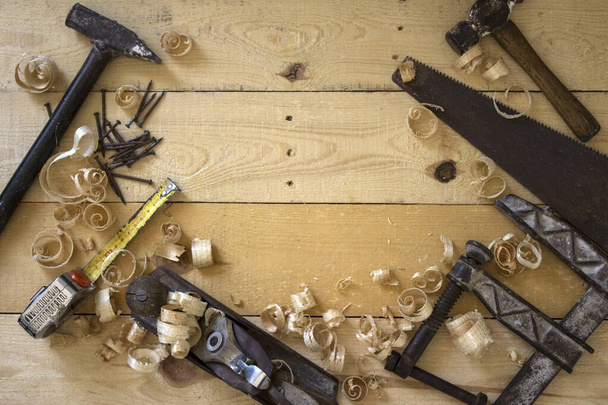 Tischlerwerkzeuge in Nahaufnahme Foto. Vintage Handsäge, Klemme, Hobelwerkzeug und Holzspäne von oben.  - Foto, Bild