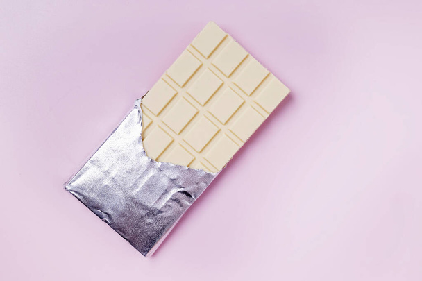 White chocolate in foil on pink background - Foto, imagen