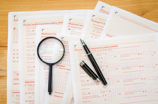 Australian tax forms with pen and magnifier. Financial document. - Zdjęcie, obraz