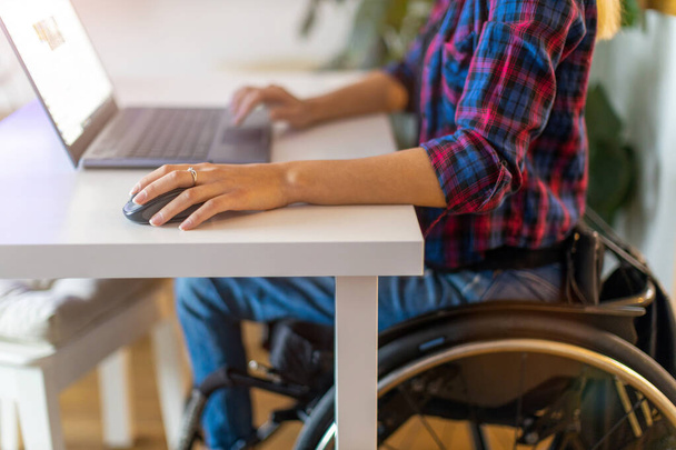 Woman in wheelchair using laptop in office - Fotoğraf, Görsel