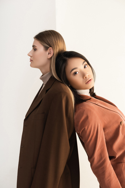 mladý stylový model pózuje s brunetkou asijské ženy na bílém - Fotografie, Obrázek