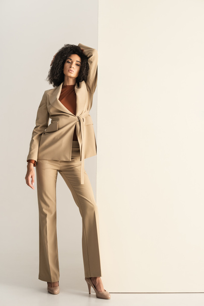 full length of curly african american woman in stylish suit posing on white - Photo, Image