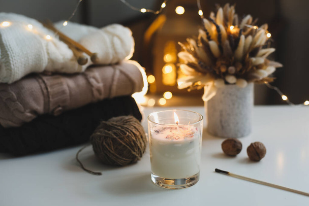 Christmas background. Candle, knitted sweater, christmas decorations and bokeh lights background. Christmas cozy mood still life - Photo, image
