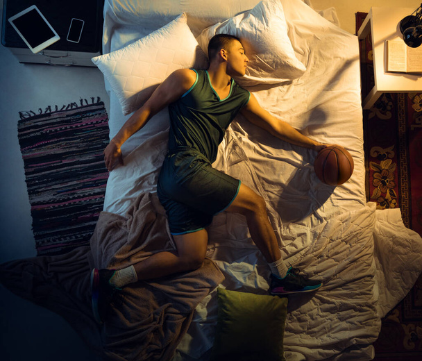 Top view of young professional basketball player sleeping at his bedroom in sportwear with ball - Valokuva, kuva