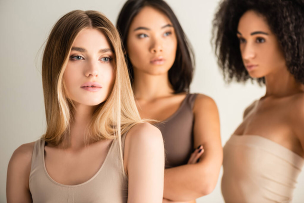 modelo loira perto de africana americana e asiática mulheres no fundo borrado isolado no branco - Foto, Imagem