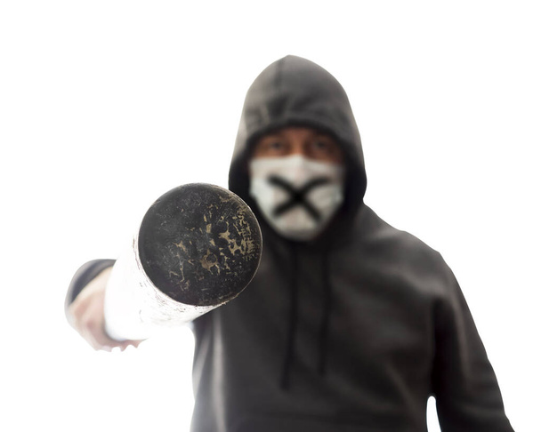 Homme en masque et sweat à capuche pokes dans le visage avec batte de baseball, isolé - Photo, image
