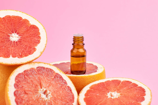 Essential citrus oil in glass bottle with fresh grapefruits. - Foto, Imagen