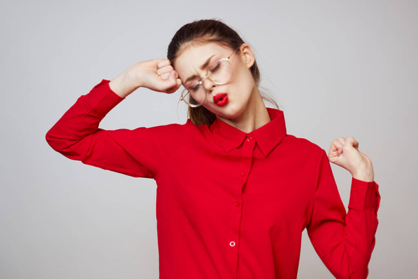 μοντέρνα γυναίκα σε ένα κόκκινο πουκάμισο σε ένα ελαφρύ φόντο διασκέδαση συναισθήματα φωτεινά γυαλιά μακιγιάζ ελκυστική εμφάνιση  - Φωτογραφία, εικόνα