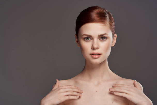 Mooie vrouw naakt schouders cosmetica schone huid charme grijs achtergrond studio - Foto, afbeelding
