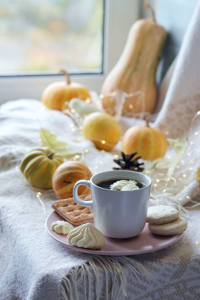 Une tasse de café, meringues, citrouilles, feuilles, une couverture chaude sur le rebord de la fenêtre, le concept de confort à la maison, détente, solitude, Action de grâce, saison d'automne - Photo, image