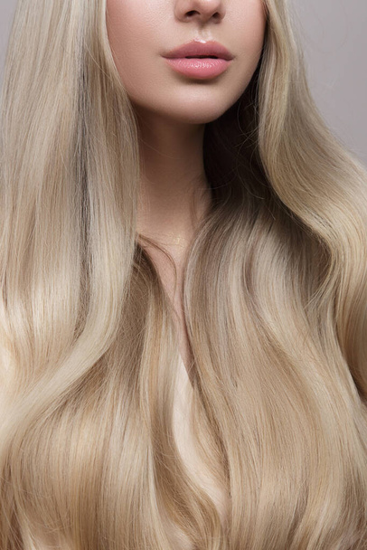 Femme blonde sur fond gris. Soins capillaires et concept de coloration. Copycpase cheveux ondulés - Photo, image