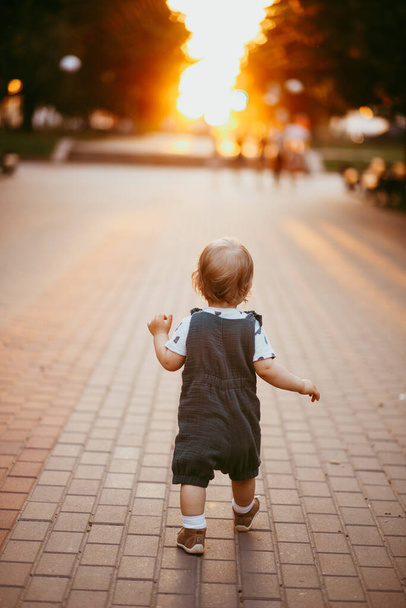 Baby runs along silhouette Boulevard on a summer evening - Foto, imagen