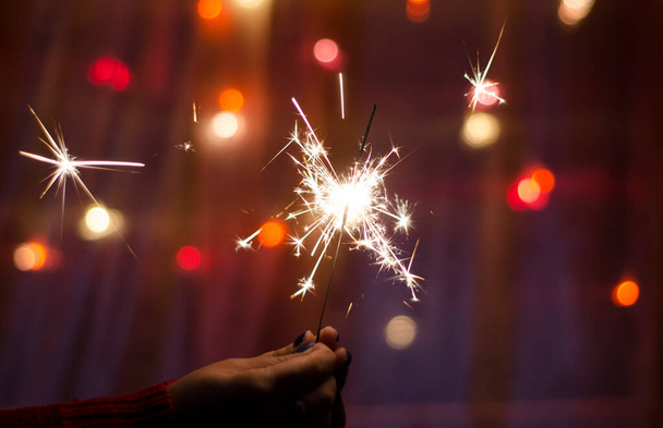Person hold a sparkler stick in a hand. Festival sparklers. Happy New year. Holidays - Foto, imagen
