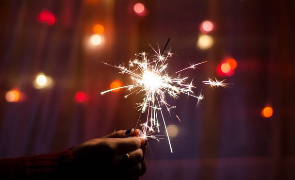 Person hold a sparkler stick in a hand. Festival sparklers. Happy New year. Holidays - Foto, Imagem