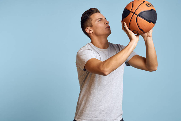 Homme avec une balle de basket sur un fond bleu modèle de jeu de sport blanc t-shirt énergie - Photo, image