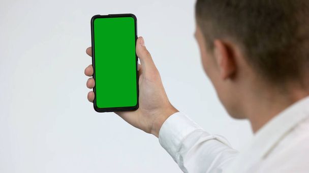 Uomo guarda schermo verde smartphone. - Foto, immagini