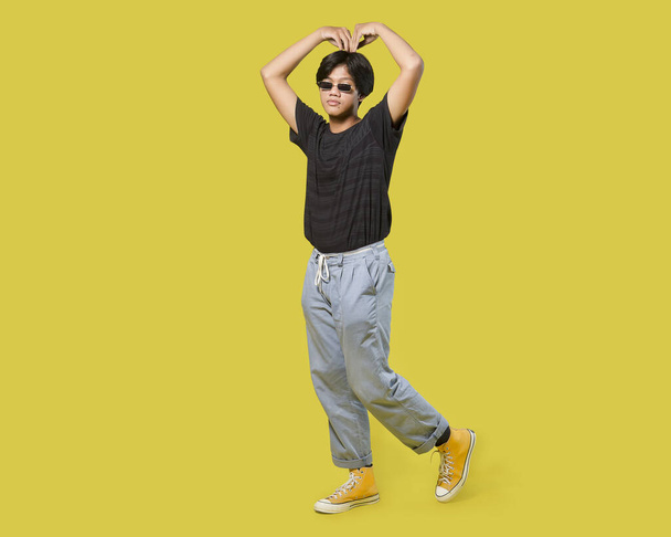 young asian man give big love gesture with his arm. isolated on yellow background. with clipping path - Foto, Imagen