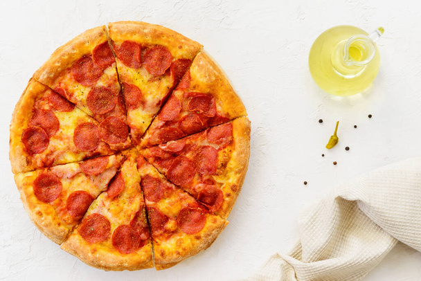 Peperoni pizza with olive oil on a light table. Horizontal orientation, top view. - Photo, Image