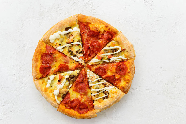 Pizza aus verschiedenen Stücken auf einem weißen Tisch. Horizontale Ausrichtung, Draufsicht, flache Lage. - Foto, Bild