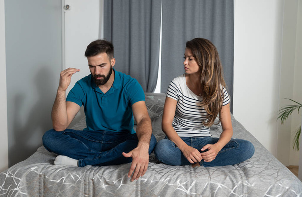 Young couple having an argue while they sitting on the bed in the bedroom because of financial problems caused by covid 19 or coronavirus quarantine and self  isolation  - Foto, Imagem