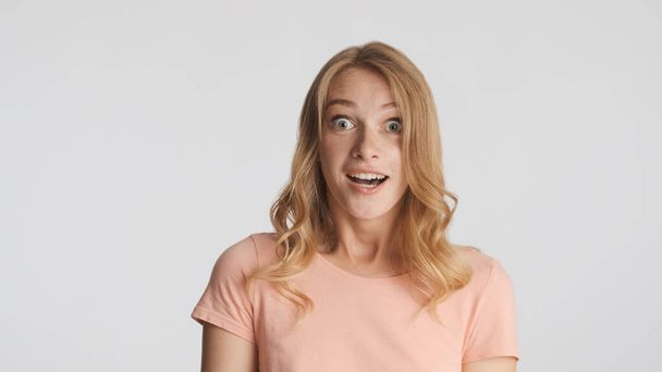 Attractive excited blond girl surprised by unexpected news on camera isolated on white background. Wow face - Foto, immagini