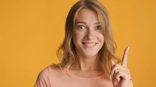 Pretty positive blond girl keep finger up having idea isolated on yellow background. New idea gesture - Photo, Image
