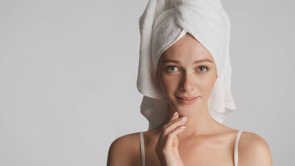 Красивая девушка с полотенцем на голове чувственно глядя в камеру на белом фоне. Место для рекламы или рекламного текста - Фото, изображение