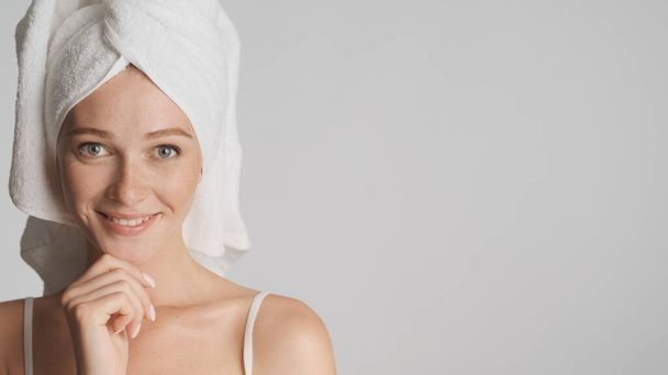 Beautiful smiling girl with towel on head happily looking in camera over white background. Copy space - Photo, Image