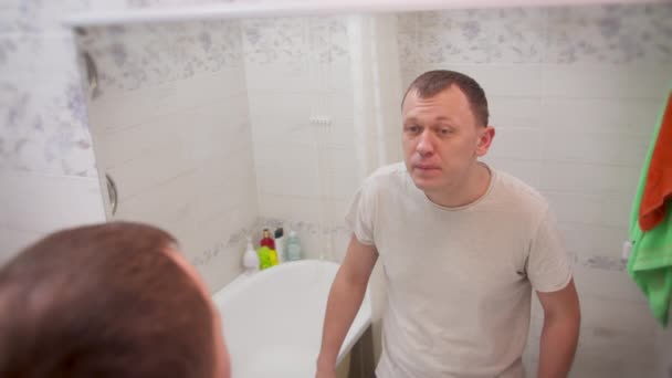 Jongeman ziek geworden, onderzoekt zichzelf in de spiegel, achteraanzicht - Video