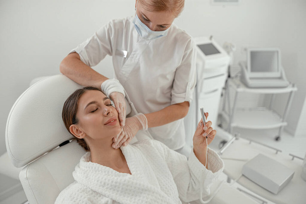 Красива здорова усміхнена біла жінка робить косметичні процедури в спа-центрі та салоні охорони здоров'я
 - Фото, зображення