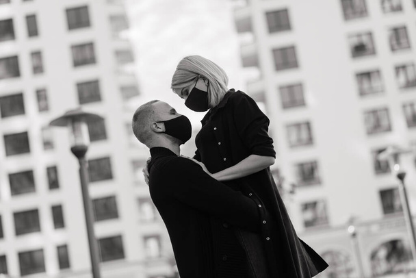 Пара в модних захисних масках, що йдуть порожньою вулицею міста під час карантину
. - Фото, зображення