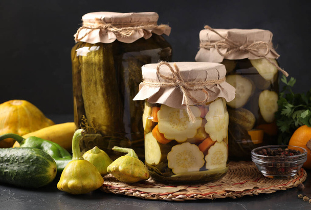 Homemade pickled patissons, cucumbers and zucchini on dark background with fresh ingredients, Closeup. Horizontal format - Photo, Image