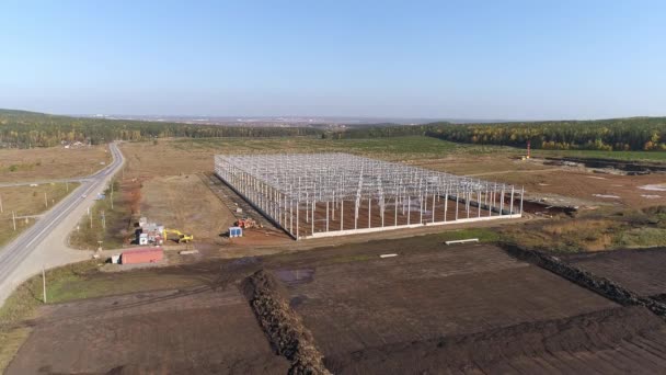 Construction Of Industrial Buildings From Metal and concrete Constructions in field next to an asphalt road. Near the forest. Autumn day. Aerial Shot - Footage, Video