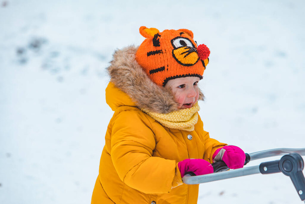 mała uśmiechnięta dziewczyna z saniami w śnieżny zimowy dzień - Zdjęcie, obraz