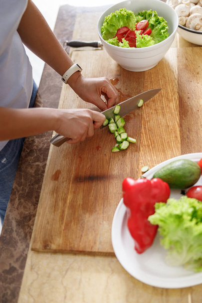 Gyönyörű, mosolygós nő készül ízletes, friss, egészséges saláta a konyhában otthon - Fotó, kép