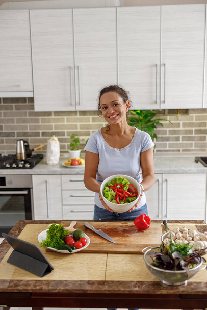 Beautiful smily handsome woman is preparing tasty fresh healthy salad at her kitchen at home - Foto, Bild