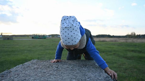 Een klein kind leert een obstakel te beklimmen. Hoge kwaliteit foto - Foto, afbeelding