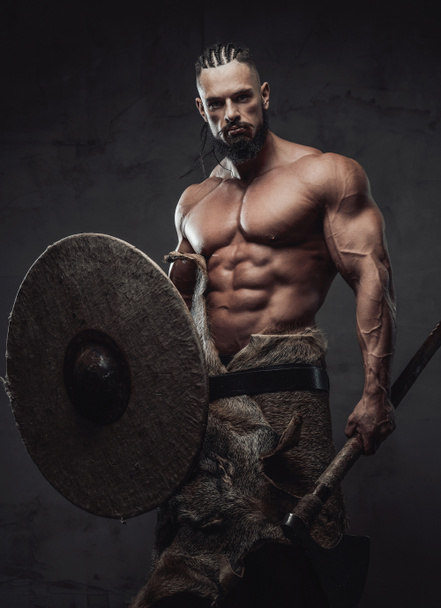 Brutal viking posing holding shield and an axe in studio - Photo, Image